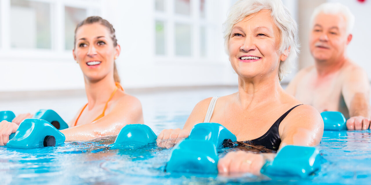 Junge und ältere Menschen bei Wassergymnastik-Physiotherapie mit Hanteln.