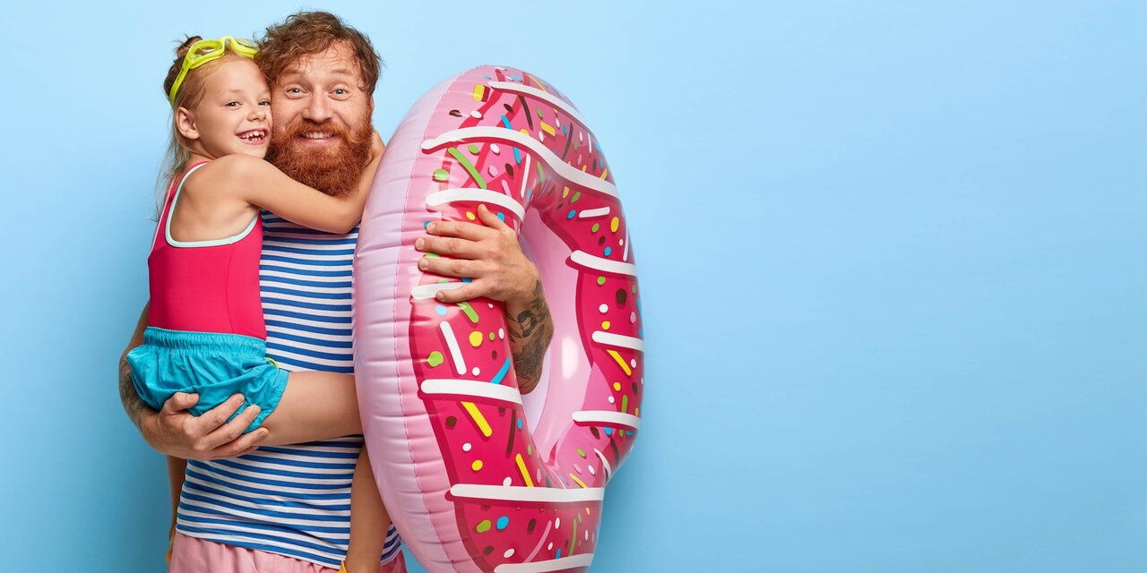 Foto zeigt fürsorglichen Vater und Tochter mit Schwimmreifen.